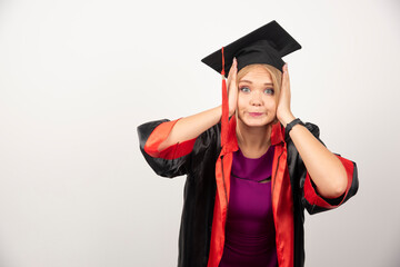 Female student in gown looking surprised on white background