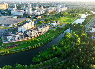Townhouses and multi-floor home near river. River in city on sunrise, aerial view. Suburb houses and multi-storey residential buildings near river. Cottages and wooden suburb house. Lake in town.