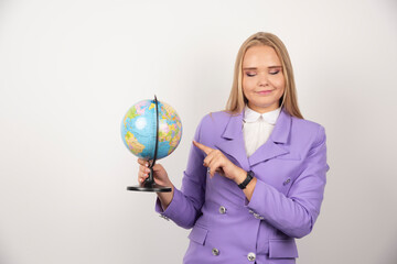 Female teacher pointing at globe on white background