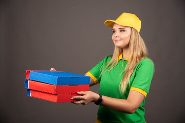 Deliverywoman in uniform giving cardboards of pizza