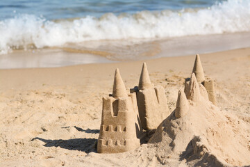 Fototapeta na wymiar Beach with sand castle near sea on sunny day