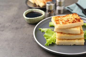 Delicious turnip cake with lettuce salad served on grey table. Space for text