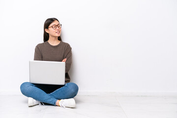 Young woman with a laptop sitting on the floor happy and smiling