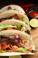 Delicious tacos with fried bacon on wooden table, closeup