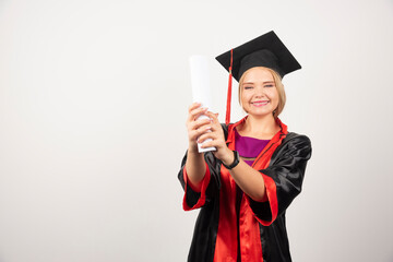 Female student in gown received diploma on white background