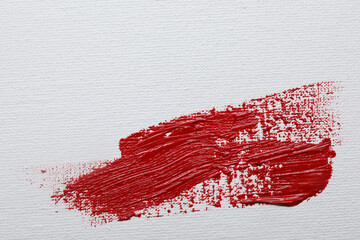 Stroke of red paint on white canvas, top view. Space for text
