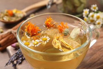 Freshly brewed tea and dried herbs on wooden table, closeup