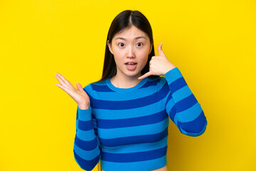 Young Chinese woman isolated on yellow background making phone gesture and doubting