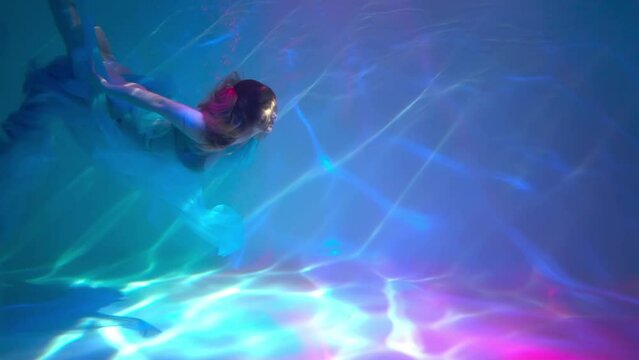 Slow Motion Mermaid. Portrait of young beautiful woman underwater.