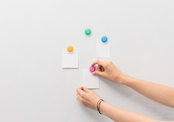 Image of white board and hand attaching pieces of paper to the magnetic board.