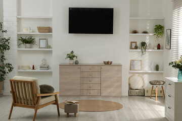 Stylish TV set mounted on wall in room
