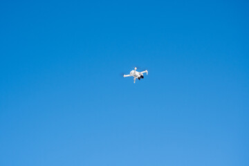 Quadcopter drone flies against the backdrop of snow-capped mountains and blue sky