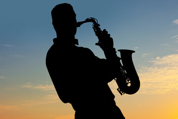 Silhouette of man playing saxophone against beautiful sky at sunset