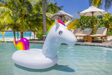 Inflatable pool toys at tropical resort pool, relaxing in infinity pool with ocean view under palm trees. Poolside with chairs umbrellas and relaxing leisure summer beach holiday mood. Freedom holiday