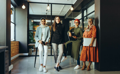 Multicultural female designers smiling at the camera in an office