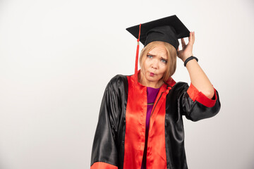 Female student in gown looking surprised on white background