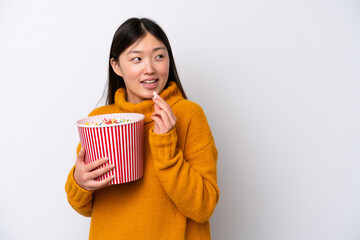 Young Chinese woman isolated on white background holding a big bucket of popcorns
