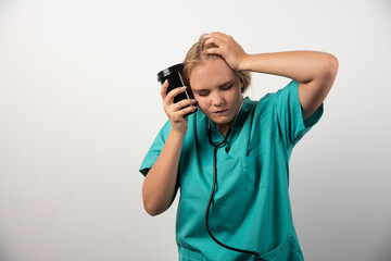 Young doctor with coffee having headache on white background