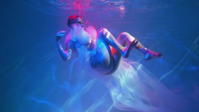 Slow Motion Beautiful woman swimming underwater with elegant dress