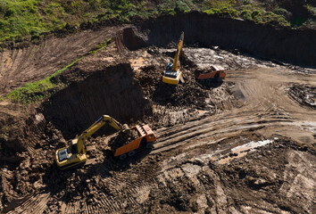 Excavator during clay mining.  mining in open pit. Aerial view of an opencast for the extraction of clay and limestone. Brick and Tile. Excavator at work in an quarry for development of clay.