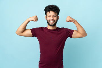 Young Moroccan man isolated on blue background doing strong gesture