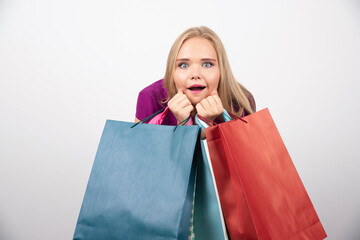 Blonde woman holding shopping bags with surprised expression