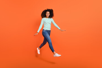 Fototapeta na wymiar Full length photo of millennial lady run wear shirt jeans footwear isolated on orange background