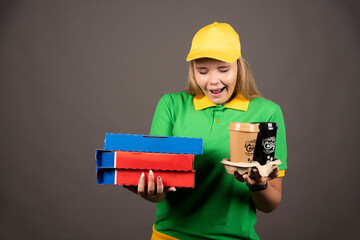 Deliverywoman looking on cups of coffee and holding cardboards of pizza