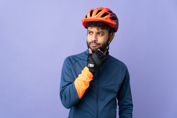 Young Moroccan cyclist man isolated on purple background and looking up