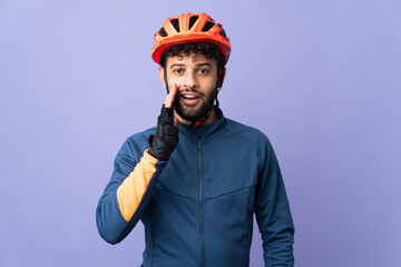 Young Moroccan cyclist man isolated on purple background with surprise and shocked facial expression - obrazy, fototapety, plakaty
