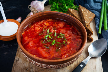 Traditional ukrainian borscht with green onion and sour cream. Delicious beet soup in bowl with rye bread