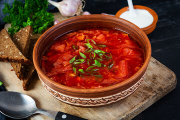 Traditional ukrainian borscht with green onion and sour cream. Delicious beet soup in bowl with rye...