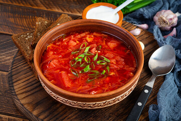 Traditional ukrainian borscht with green onion and sour cream. Delicious beet soup in bowl with rye bread