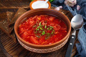 Traditional ukrainian borscht with green onion and sour cream. Delicious beet soup in bowl with rye bread