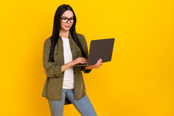 Photo of nice millennial lady look laptop wear eyewear khaki shirt jeans isolated on yellow background
