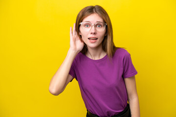 Young English woman isolated on yellow background listening to something by putting hand on the ear