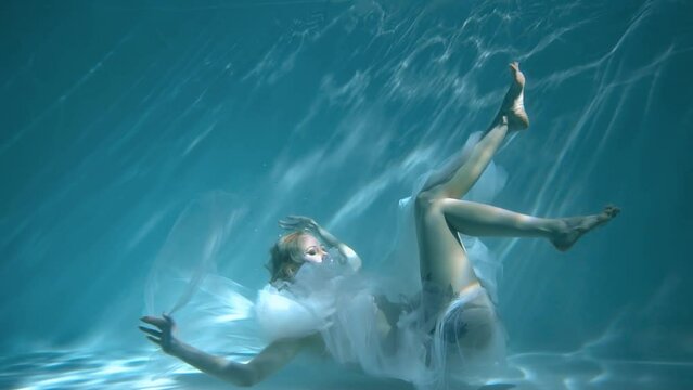Slow Motion Underwater woman portrait with white dress into the sea.