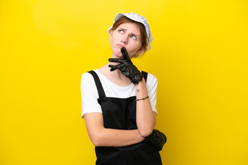 Young English fisherwoman isolated on yellow background having doubts while looking up