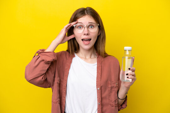 Young English woman with a bottle of water isolated on yellow background with surprise expression