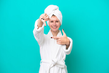 Young woman in a bathrobe isolated on blue background focusing face. Framing symbol