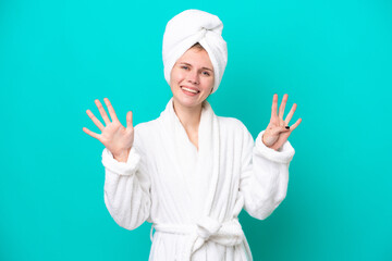 Young woman in a bathrobe isolated on blue background counting nine with fingers