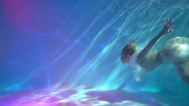 Slow Motion Woman in white dress underwater dancing around splashes of water.