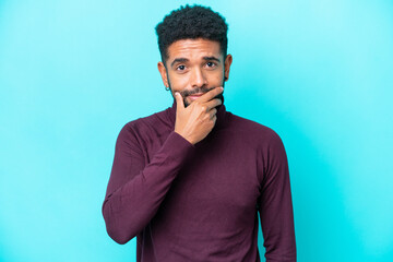 Young Brazilian man isolated on blue background thinking
