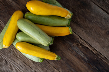 Multi-colored zucchini yellow, green, white, orange on the wooden table close-up. Food background. Fresh harvested courgette, cropped summer squash. Picked green courgettes. Still life in kitchen.