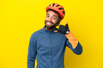 Young cyclist Brazilian man isolated on yellow background making phone gesture. Call me back sign