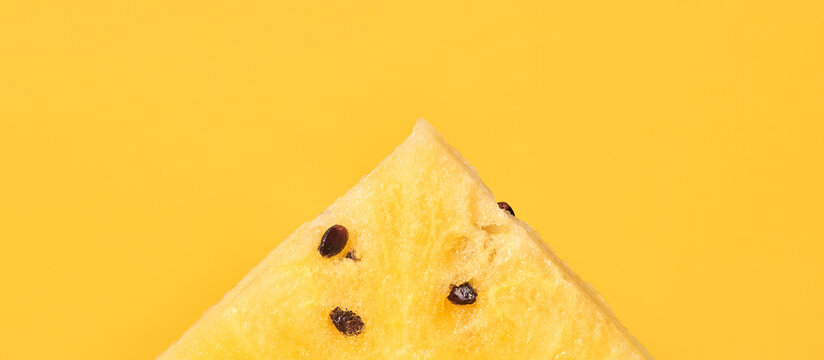 One piece of yellow watermelon with seeds on yellow background, delicious refreshing fruit