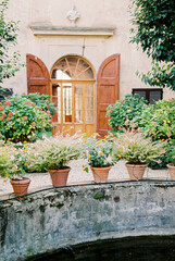 Fototapeta na wymiar Blooming flowerpots stand on a stone fence near an old villa