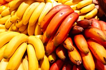 Foto op Plexiglas The standard yellow and the more exotic red bananas in bunches on a farmers market stall on Tenerife, Canary Islands, Spain. © agenturfotografin