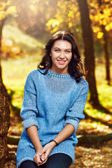 Beautiful young smiling girl posing in warm autumn forest