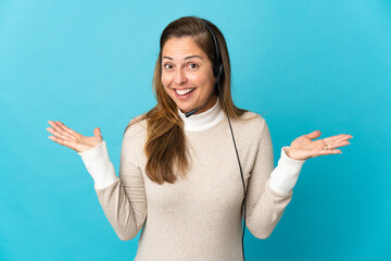 Young telemarketer woman over isolated blue background with shocked facial expression